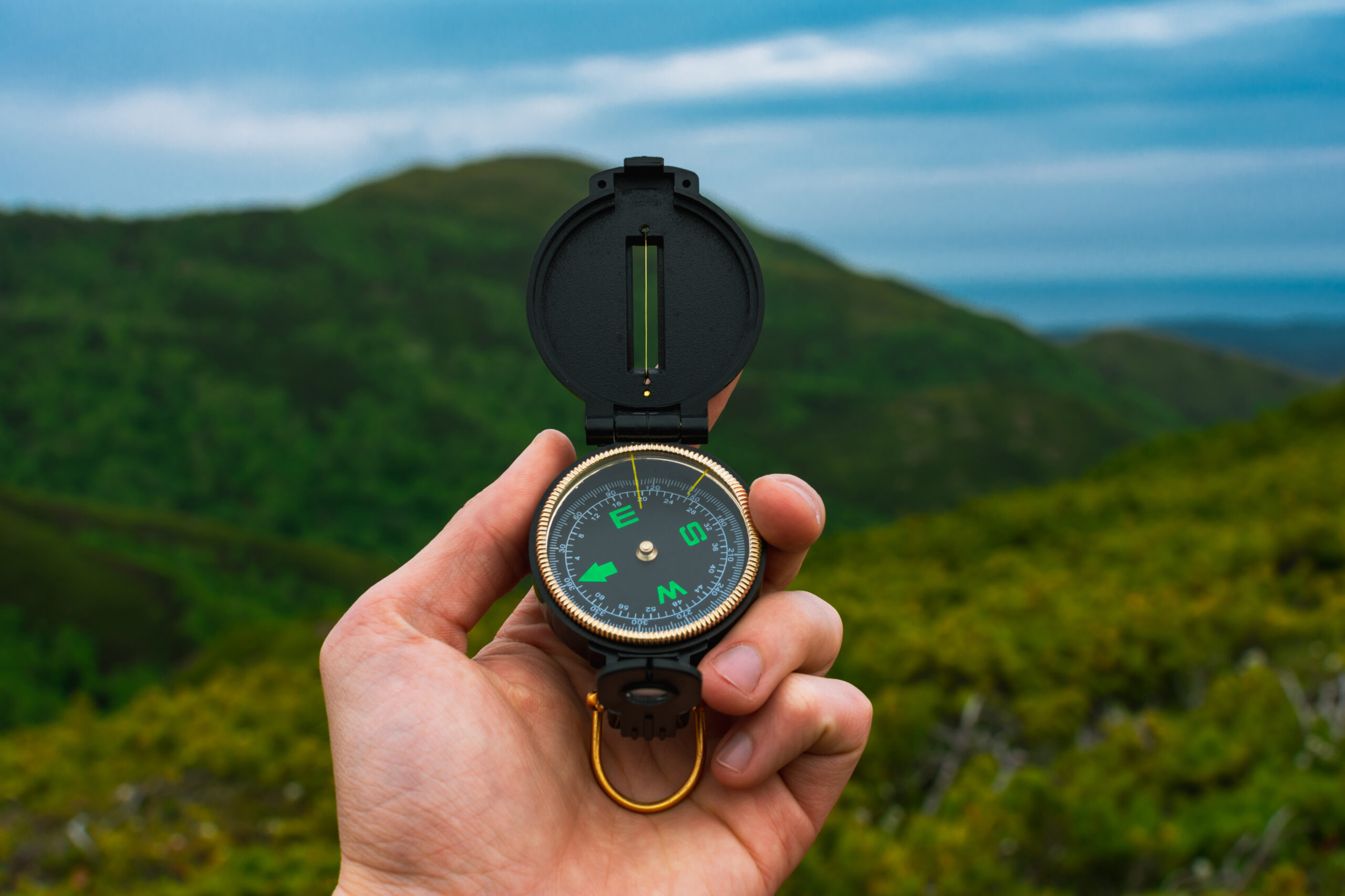 Compass pointing toward distant mountaintop, representing clear direction and long-term vision"